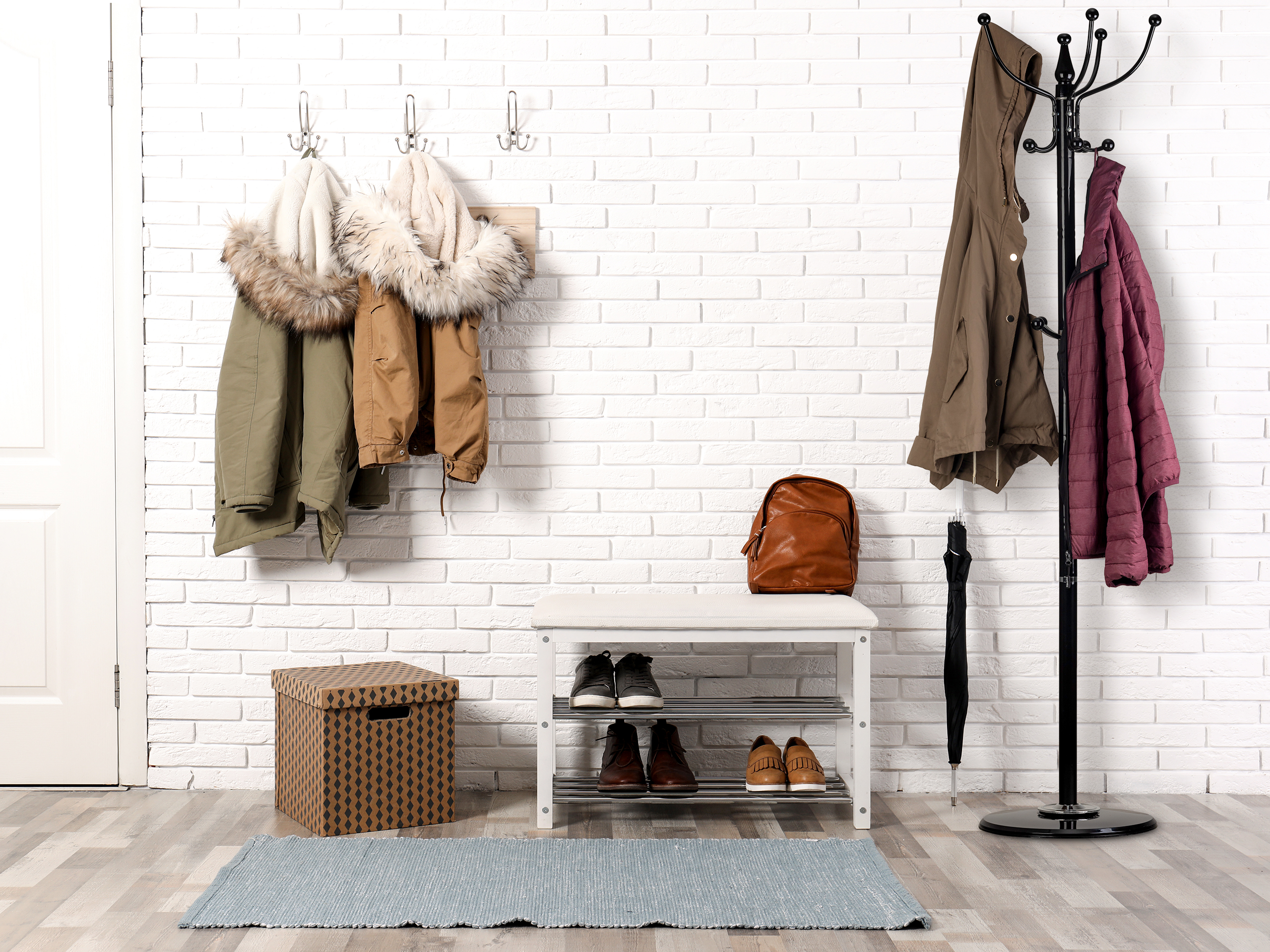 Stylish hallway interior with shoe rack and hanging clothes on b