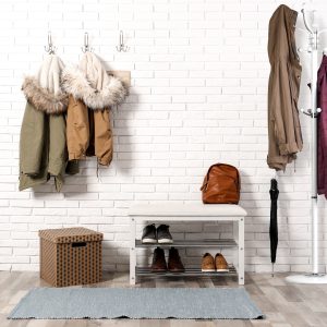 Stylish hallway interior with shoe rack and hanging clothes on b
