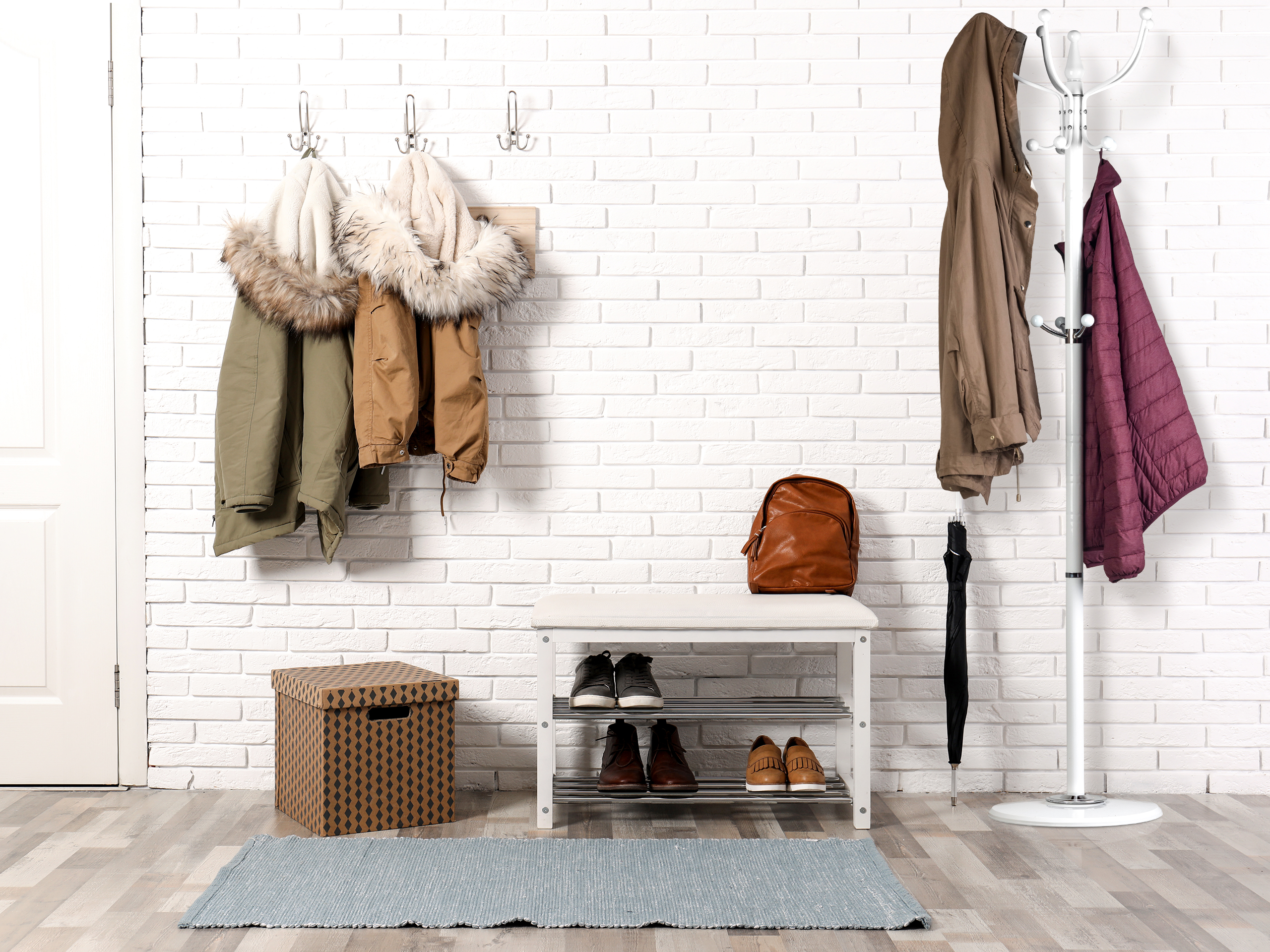 Stylish hallway interior with shoe rack and hanging clothes on b