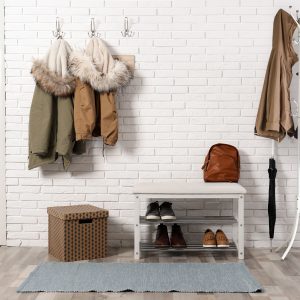 Stylish hallway interior with shoe rack and hanging clothes on b