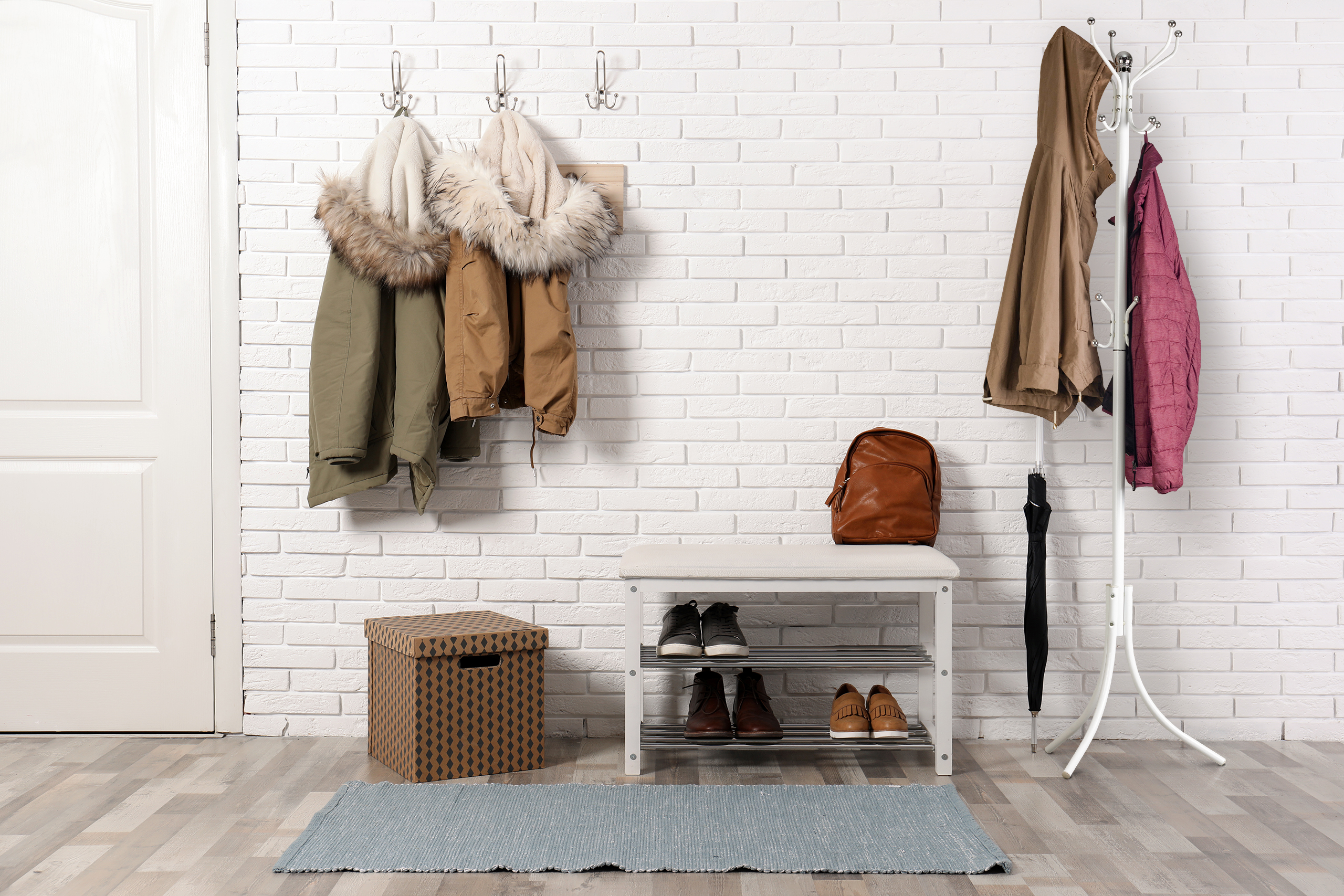 Stylish hallway interior with shoe rack and hanging clothes on b