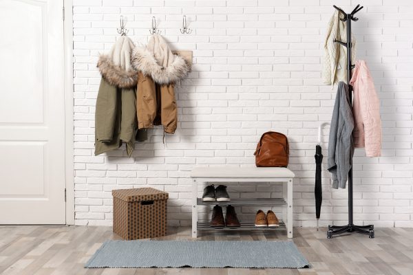 Stylish hallway interior with shoe rack and hanging clothes on b