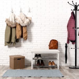 Stylish hallway interior with shoe rack and hanging clothes on b