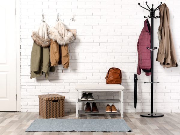 Stylish hallway interior with shoe rack and hanging clothes on b