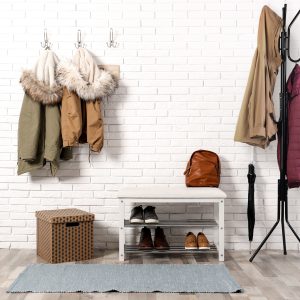 Stylish hallway interior with shoe rack and hanging clothes on b