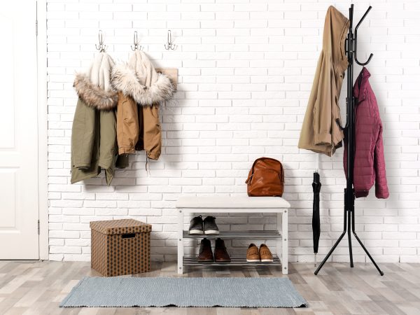 Stylish hallway interior with shoe rack and hanging clothes on b