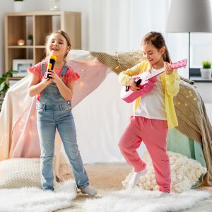 girls with guitar and microphone playing at home