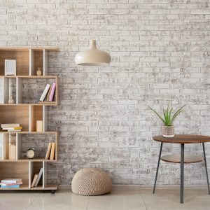 Interior of modern room with bookcase, pouf and lamp