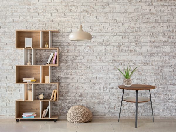 Interior of modern room with bookcase, pouf and lamp